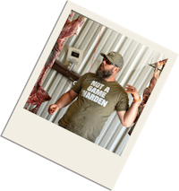 a man in a t - shirt standing next to a piece of meat